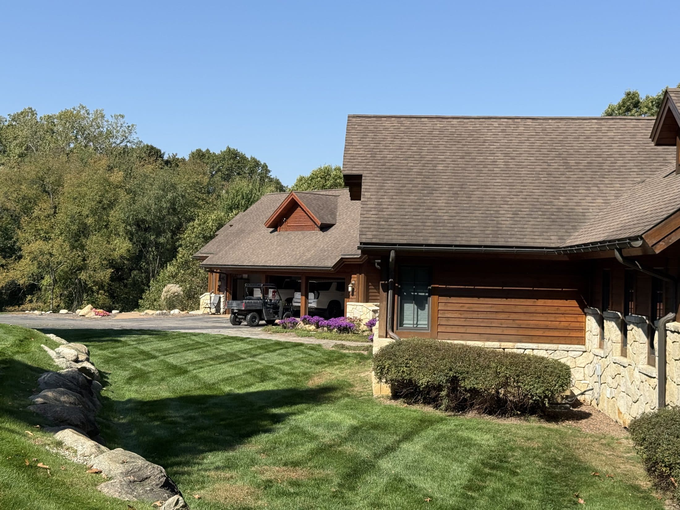A manicured striped lawn and tidy landscaped beds beside a stone home