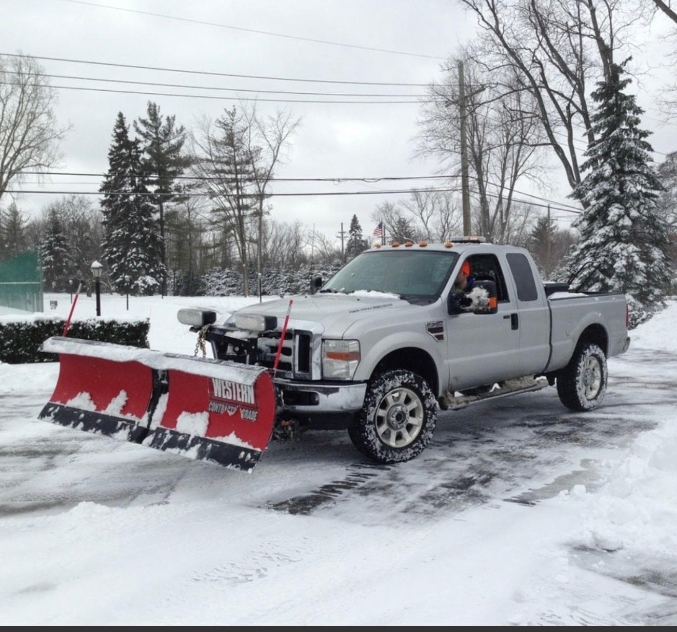 A pickup truck with a Western snow plow clearing a snow-covered lot in winter